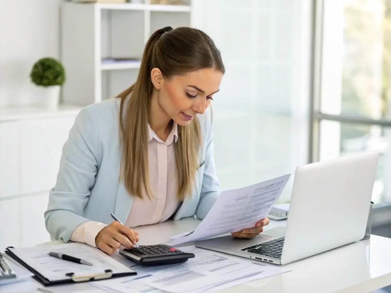 A person sitting at a desk, reviewing tax documents with a calculator and pen in hand, symbolizing individual tax preparation.